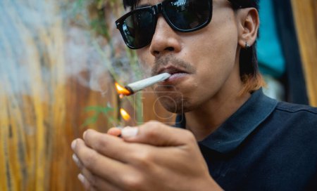 Téléchargez les photos : Jeune homme fumant des cigarettes avec de la marijuana médicale. - en image libre de droit