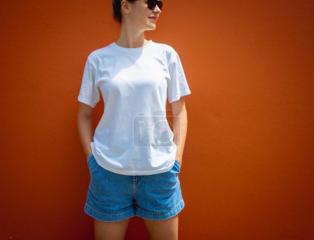 Photo for Female model wearing white blank t-shirt on the background of an orange wall - Royalty Free Image