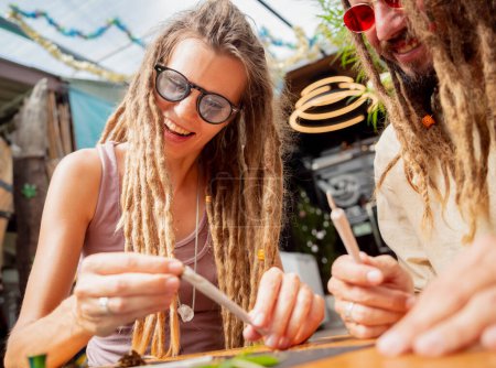 Foto de Estilo hippie pareja haciendo cigarrillos de marihuana medicinal. - Imagen libre de derechos