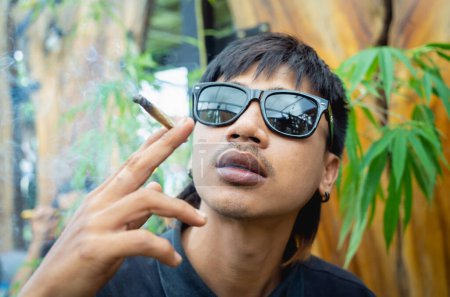 Foto de Hombre joven fumando cigarrillos con marihuana medicinal. - Imagen libre de derechos