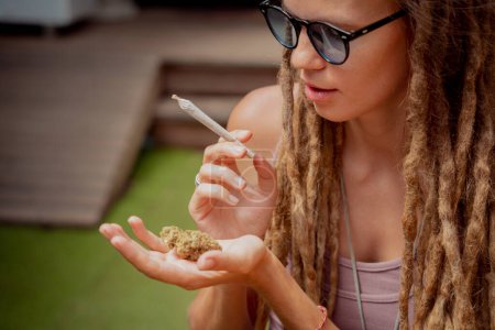 Téléchargez les photos : Hippie style femme fumant des cigarettes avec de la marijuana médicale. - en image libre de droit