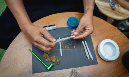 Téléchargez les photos : Jeune homme faisant des cigarettes avec de la marijuana médicale. - en image libre de droit