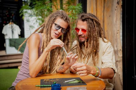 Photo for Hippie style couple making medical marijuana cigarettes. - Royalty Free Image