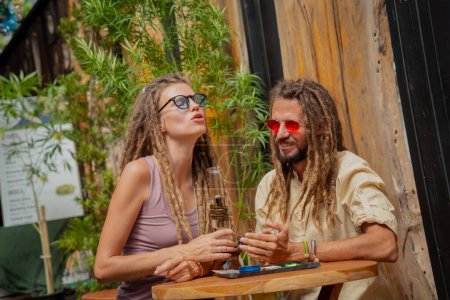 Photo for Hippie style couple smoking medical marijuana using a bong. - Royalty Free Image