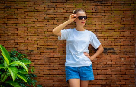 Photo for Female model wearing white blank t-shirt on the background of an bricks wall - Royalty Free Image