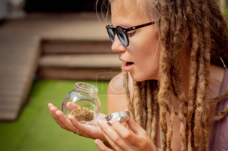 Photo for Hippie style woman examines joints and buds of medical marijuana - Royalty Free Image