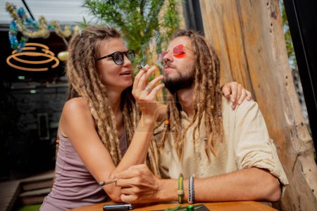 Téléchargez les photos : Hippie style couple fumer des cigarettes avec de la marijuana médicale. - en image libre de droit