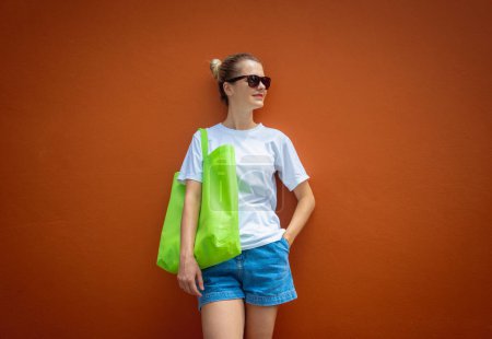 Foto de Modelo femenino con camiseta blanca en blanco en el fondo de una pared naranja - Imagen libre de derechos