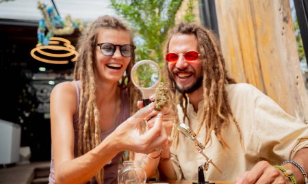 Photo for Hippie style couple examines under a magnifying glass the joints and buds of medical marijuana. - Royalty Free Image