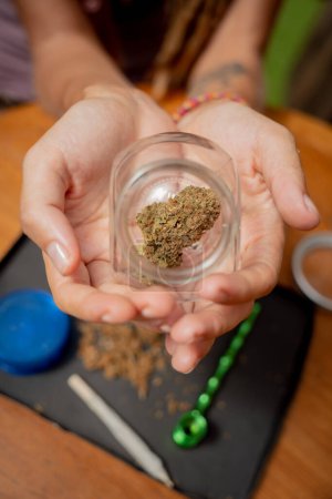 Téléchargez les photos : Hippie style femme examine les articulations et les bourgeons de marijuana médicale - en image libre de droit