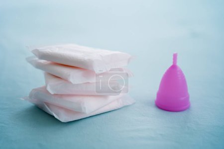 Téléchargez les photos : Menstrual cup and pads on a blue background, concept of critical days. - en image libre de droit