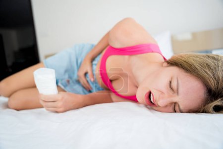 Foto de Beautiful woman feels pain during menstruation on the bed. - Imagen libre de derechos