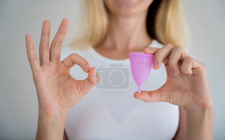 Téléchargez les photos : Young beautiful woman at home holding a menstrual cup in her hands. - en image libre de droit