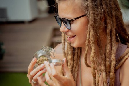 Téléchargez les photos : Hippie style femme examine les articulations et les bourgeons de marijuana médicale - en image libre de droit