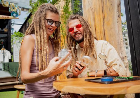 Foto de Estilo hippie pareja examina articulaciones y brotes de marihuana medicinal - Imagen libre de derechos