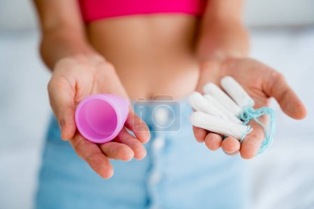 Foto de Mujer joven sosteniendo en sus manos la copa menstrual y tampones. - Imagen libre de derechos