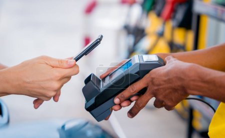 Téléchargez les photos : Woman using contactless payment by mobile phone with QR code at car filling station. - en image libre de droit