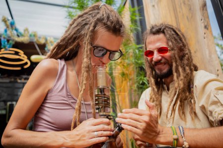 Foto de Hippie style couple smoking medical marijuana using a bong. - Imagen libre de derechos