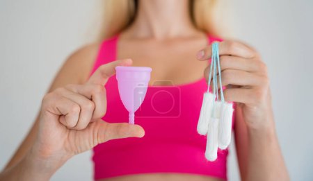 Photo for Young woman holding at her hands menstrual cup and tampons. - Royalty Free Image
