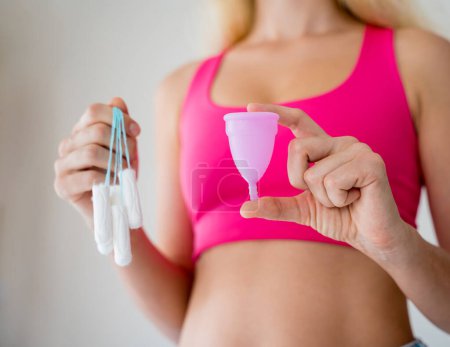 Photo for Young woman holding at her hands menstrual cup and tampons. - Royalty Free Image
