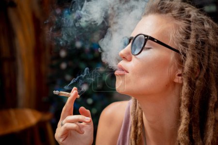 Téléchargez les photos : Hippie style femme fumant des cigarettes avec de la marijuana médicale. - en image libre de droit