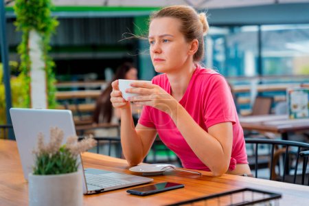 Photo for Young woman drinking coffee at the table with notebook in cafe. - Royalty Free Image