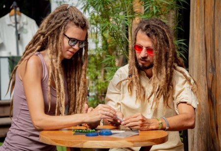 Photo for Hippie style couple making medical marijuana cigarettes. - Royalty Free Image