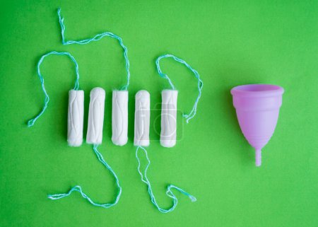 Téléchargez les photos : Menstrual cup, tampons on a green background, concept of critical days. - en image libre de droit