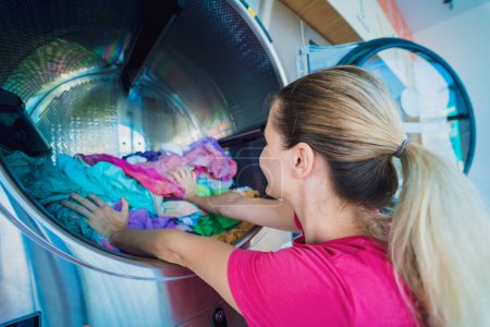 Foto de Joven hermosa mujer lava y seca la ropa en la lavandería. - Imagen libre de derechos