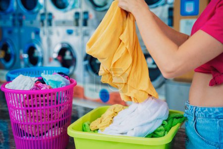 Foto de Joven hermosa mujer lava y seca la ropa en la lavandería. - Imagen libre de derechos