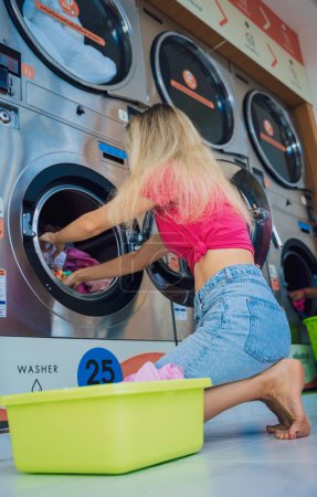 Photo for Young beautiful woman washes and dries clothes in the laundry. - Royalty Free Image