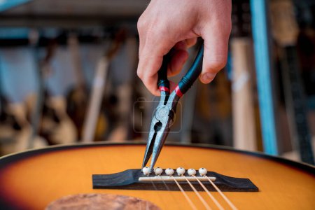 Photo for Young musician changing strings on a classical guitar in a guitar shop. - Royalty Free Image