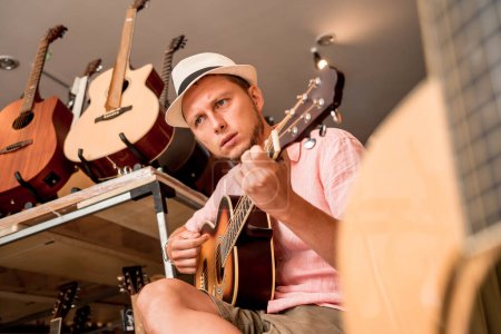 Foto de Joven músico probando guitarra clásica en una tienda de guitarra. - Imagen libre de derechos