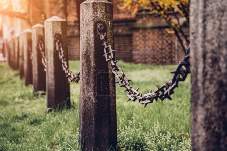 Foto de Antiguos postes de piedra con cadenas sobre un fondo de hierba verde. - Imagen libre de derechos