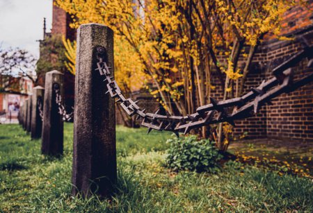 Foto de Antiguos postes de piedra con cadenas sobre un fondo de hierba verde. - Imagen libre de derechos
