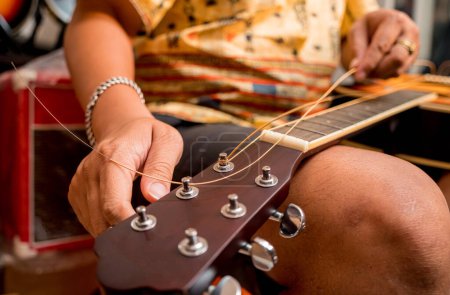 Photo for Young musician changing strings on a classical guitar in a guitar shop. - Royalty Free Image