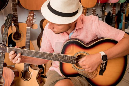 Photo for Young musician testing classical guitar in a guitar shop. - Royalty Free Image