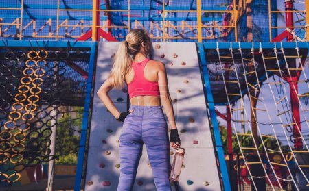 Photo for Athletic young woman working out and climbing at the artificial rock in training camp - Royalty Free Image