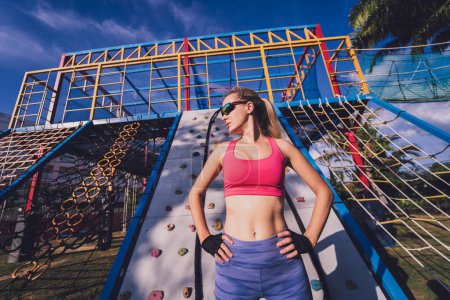 Foto de Mujer joven atlética haciendo ejercicio y escalando en la roca artificial en el campo de entrenamiento - Imagen libre de derechos