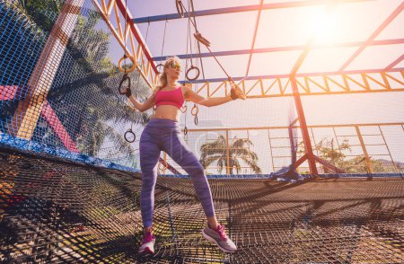 Téléchargez les photos : Jeune femme sportive faisant de l'exercice avec des anneaux de gymnastique dans un camp d'entraînement. - en image libre de droit