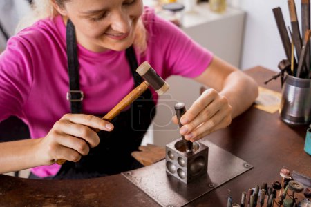 Photo for Young female jeweler making jewelry in workshop. - Royalty Free Image