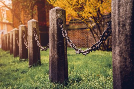 Photo for Old stone posts with chains on a background of green grass. - Royalty Free Image