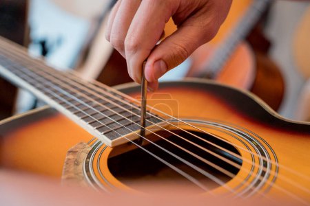 Photo for Young musician tuning a classical guitar in a guitar shop. - Royalty Free Image