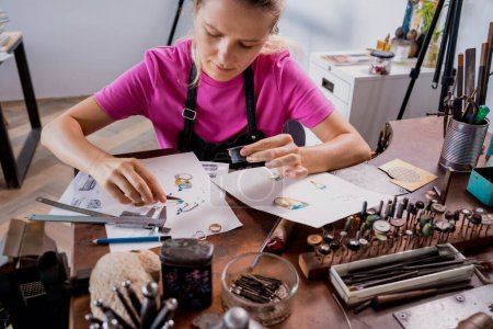 Téléchargez les photos : Jeune bijoutière fabriquant des bijoux en atelier. - en image libre de droit