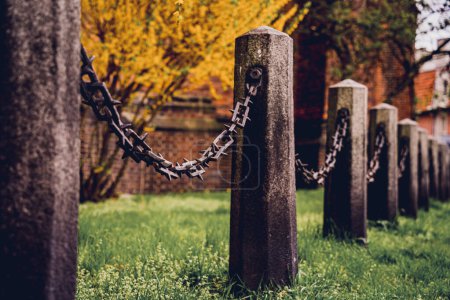 Photo for Old stone posts with chains on a background of green grass. - Royalty Free Image