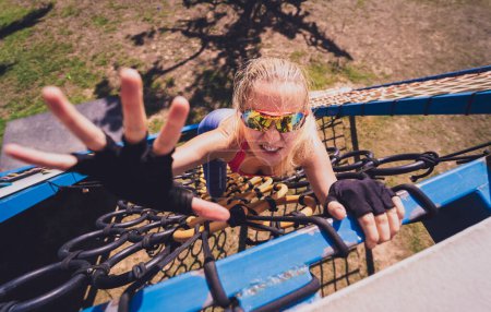 Téléchargez les photos : Jeune femme athlétique travaillant et escaladant des cordes au camp d'entraînement à la corde - en image libre de droit