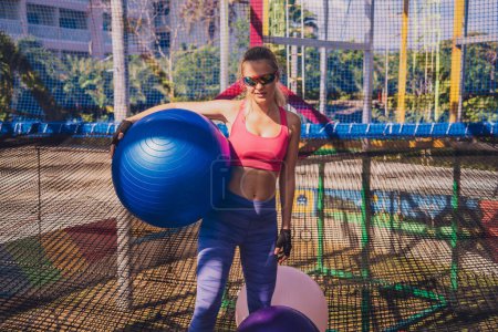 Téléchargez les photos : Jeune femme athlétique faisant de l'exercice avec du fitball dans un camp d'entraînement. - en image libre de droit