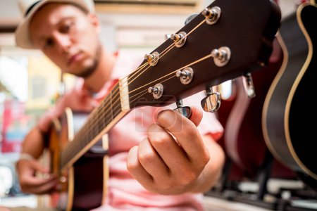 Photo for Young musician tuning a classical guitar in a guitar shop. - Royalty Free Image