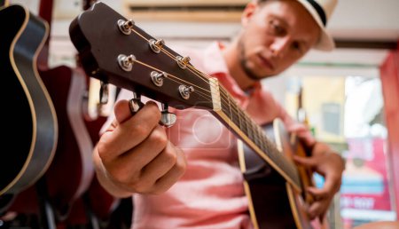 Foto de Joven músico afinando una guitarra clásica en una tienda de guitarra. - Imagen libre de derechos