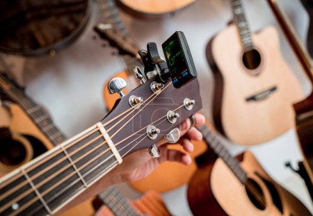 Téléchargez les photos : Jeune musicien accordant une guitare classique dans un magasin de guitare. - en image libre de droit